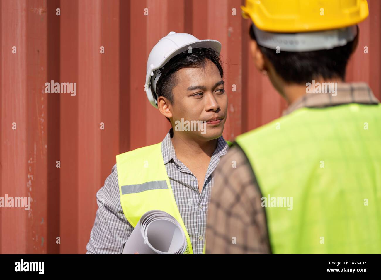 Project Coordination. Young engineers collaborating on logistics in a construction setting. Stock Photo