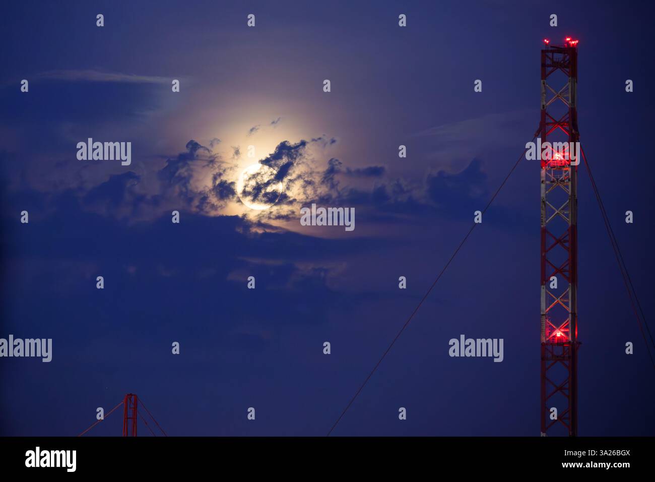 Lunar eclipse at dusk with transmission tower Stock Photo