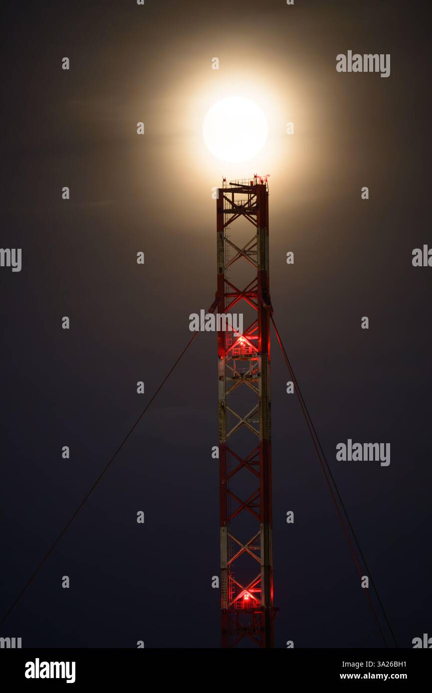 Lunar eclipse at dusk with transmission tower Stock Photo