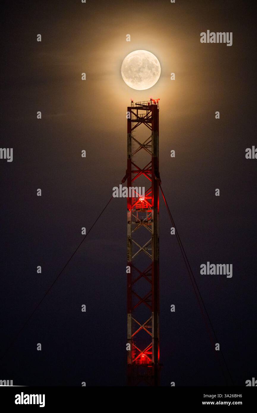 Lunar eclipse at dusk with transmission tower Stock Photo
