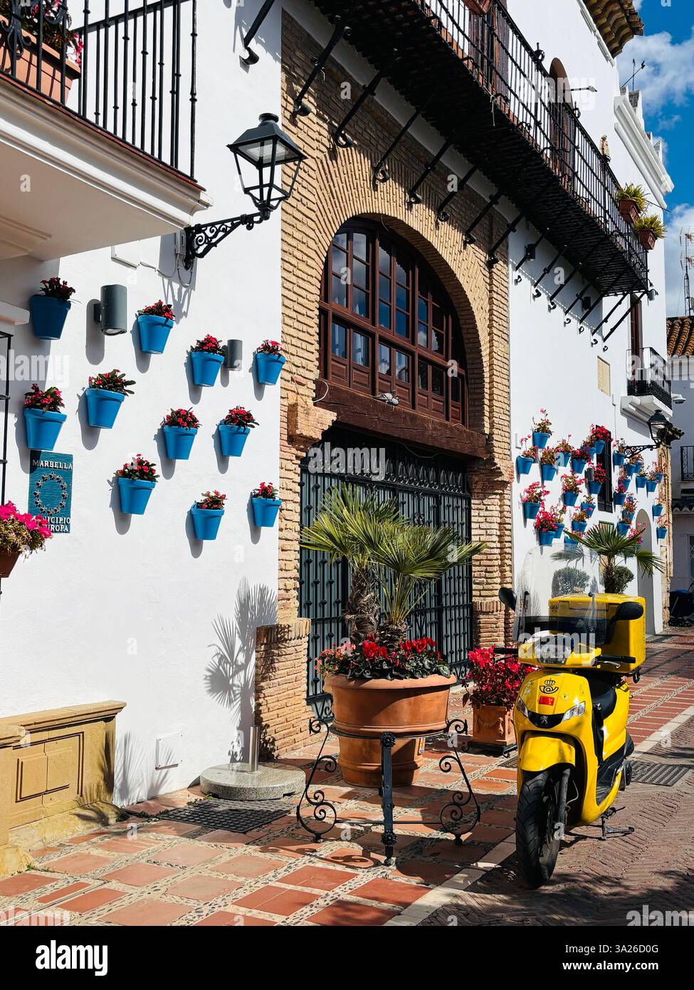 yellow moped in a spanish street with blue pots and a white wash wall - Smartphone Captured Stock Image