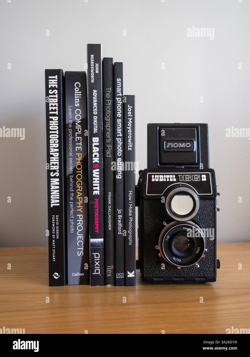 Stack of photography books on a wooden table with a Lubitel film camera; concept for photography as a hobby, pastime, interest etc Stock Photo
