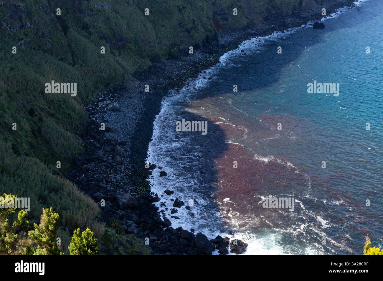Aerial view of a steep, rocky coastline where ocean waves crash against ...