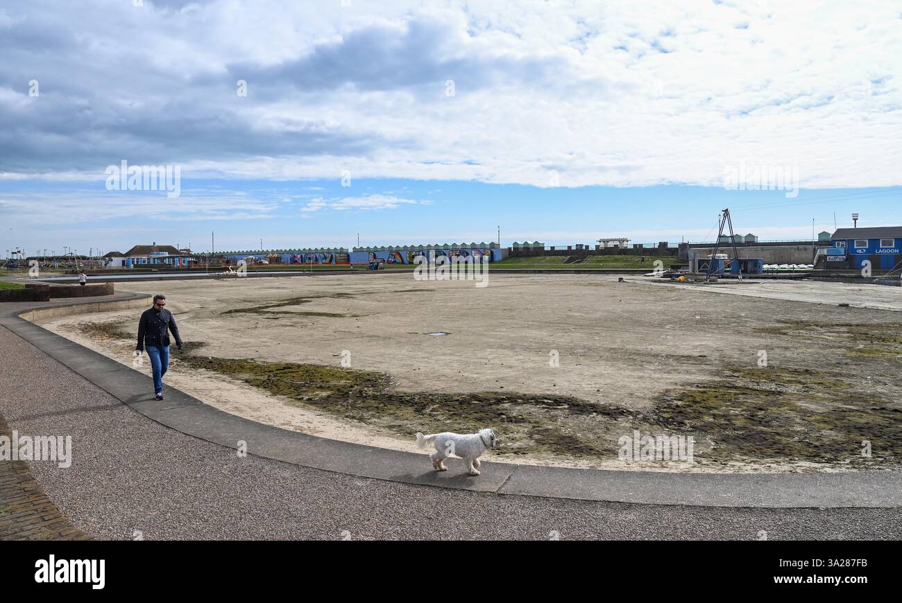 Brighton UK 12th March 2025 A dog walker passes by Hove Lagoon which has been drained for