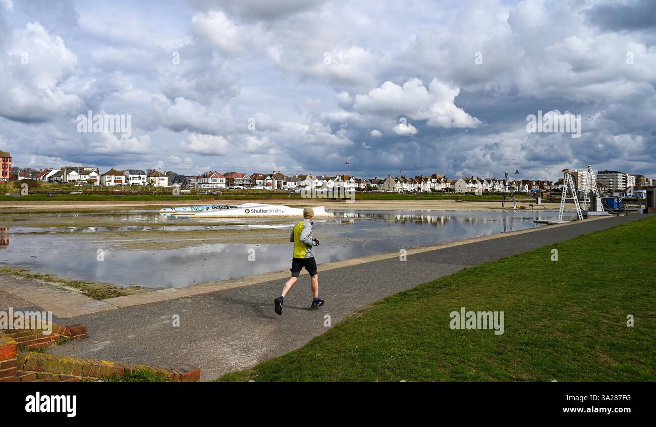 Brighton UK 12th March 2025 A runner passes by Hove Lagoon which has been drained for