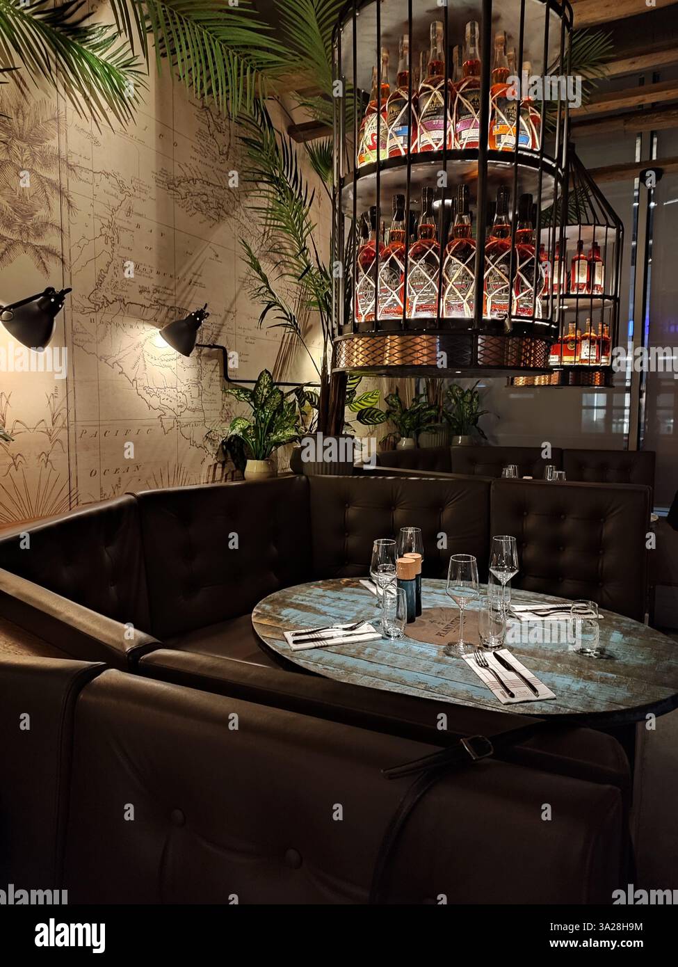 Round table set for dinner under chandelier of rum bottles in a stylish Stockholm restaurant interior - Smartphone Captured Stock Image