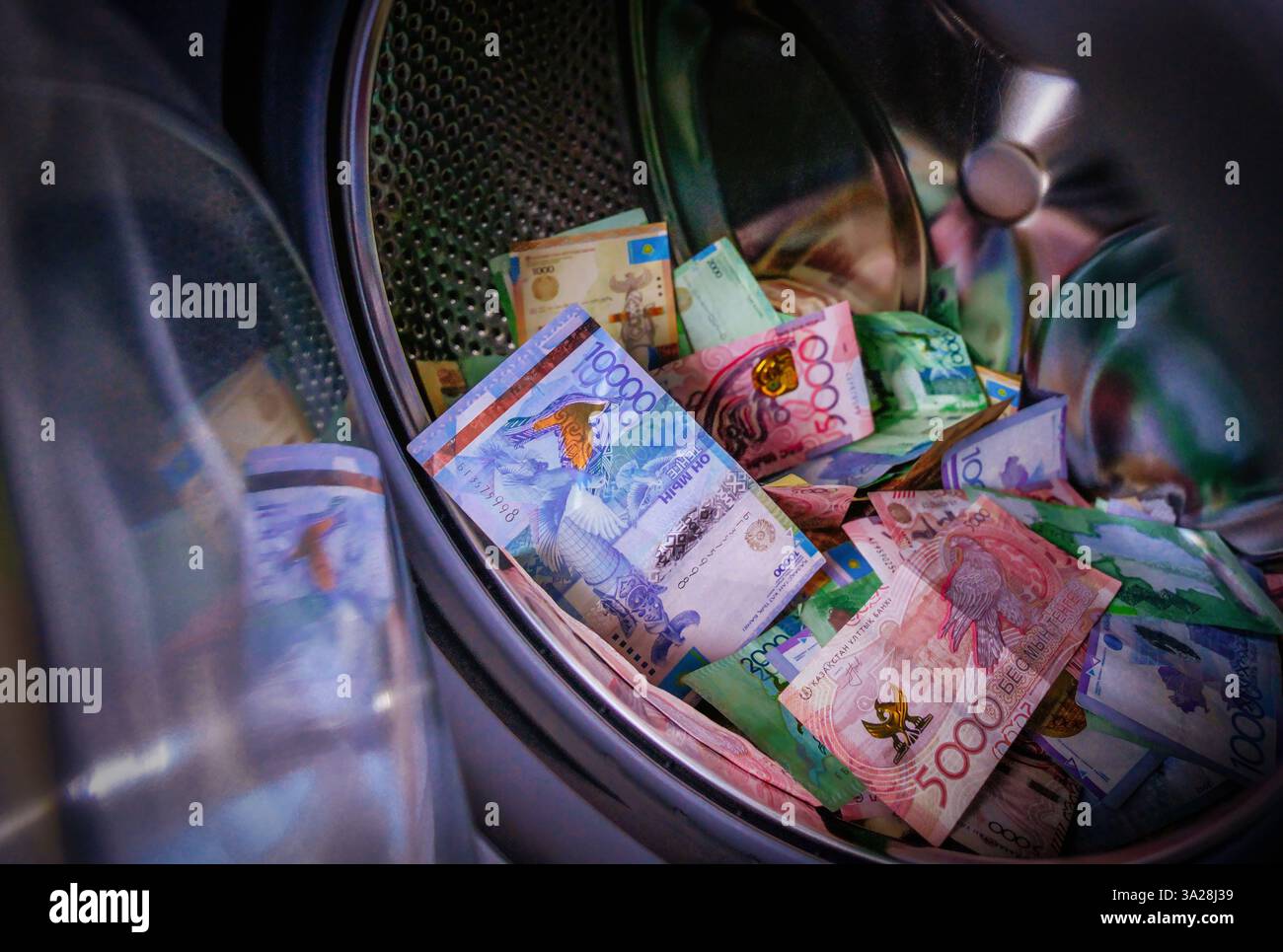 A pile of tenge banknotes lies in the washing machine. Money laundering. Criminal assets Stock Photo