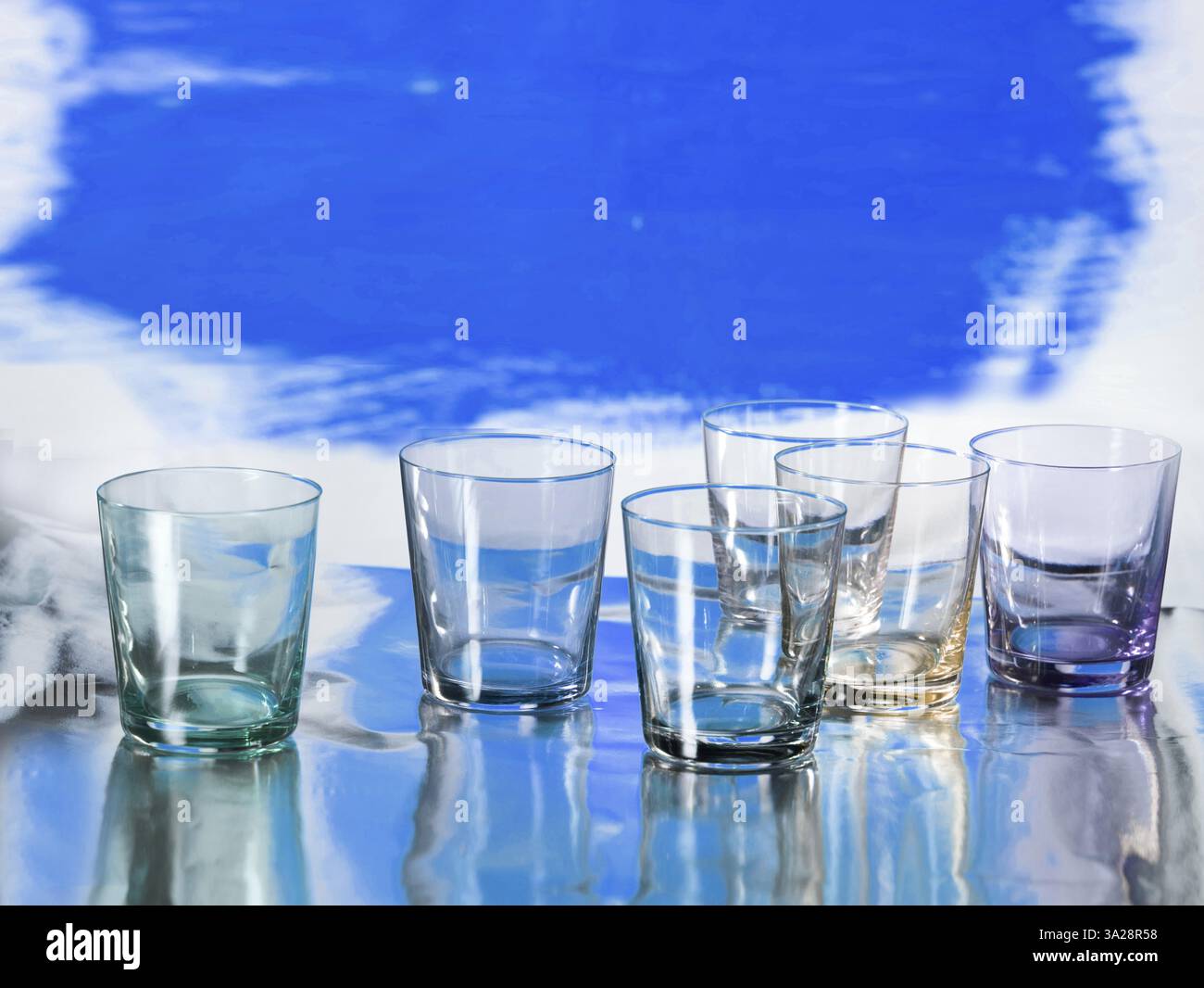 Various glasses on silver foil, blue coloured surface behind, studio shot Stock Photo