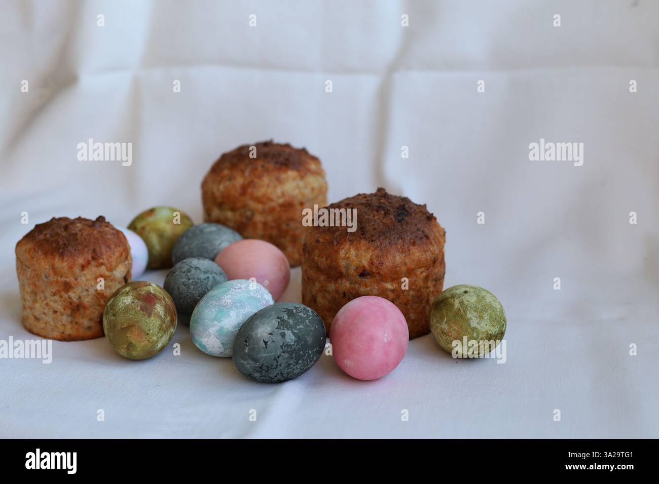 three Easter cakes and colorful eggs on a white tablecloth Stock Photo