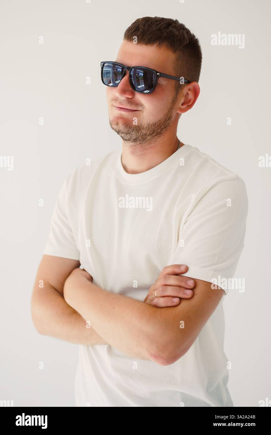 A stylish young man poses confidently in his trendy sunglasses ...
