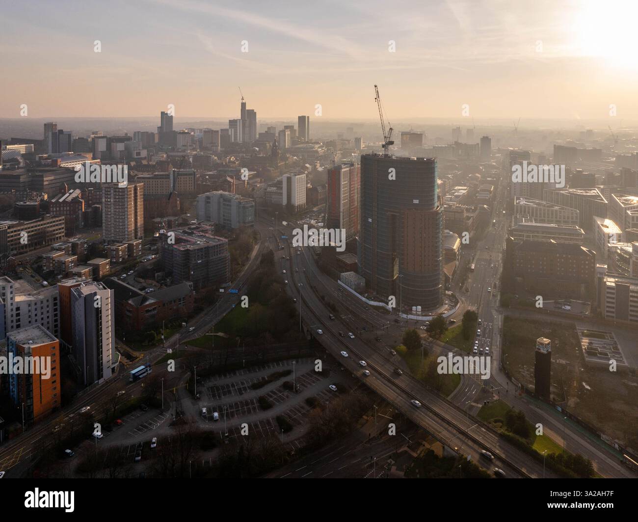 A captivating aerial view showcases Leeds city centre during dawn with beautiful golden hour lighting. The urban skyline and cityscape highlight ongoi Stock Photo
