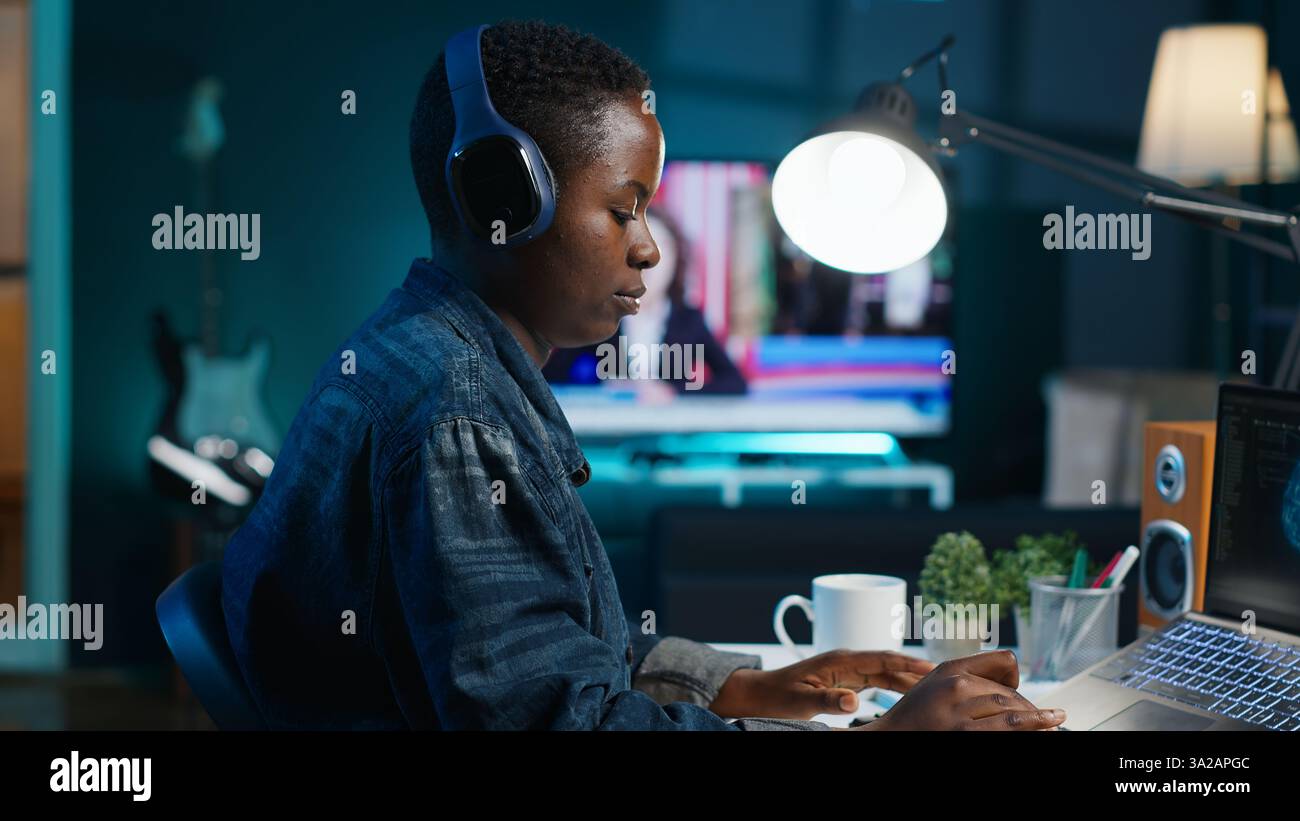 Programmer in living room office typing on keyboard, updating artificial intelligence neural networks, writing binary code scripts. Freelancing system administrator upgrading high tech AI, camera A Stock Photo