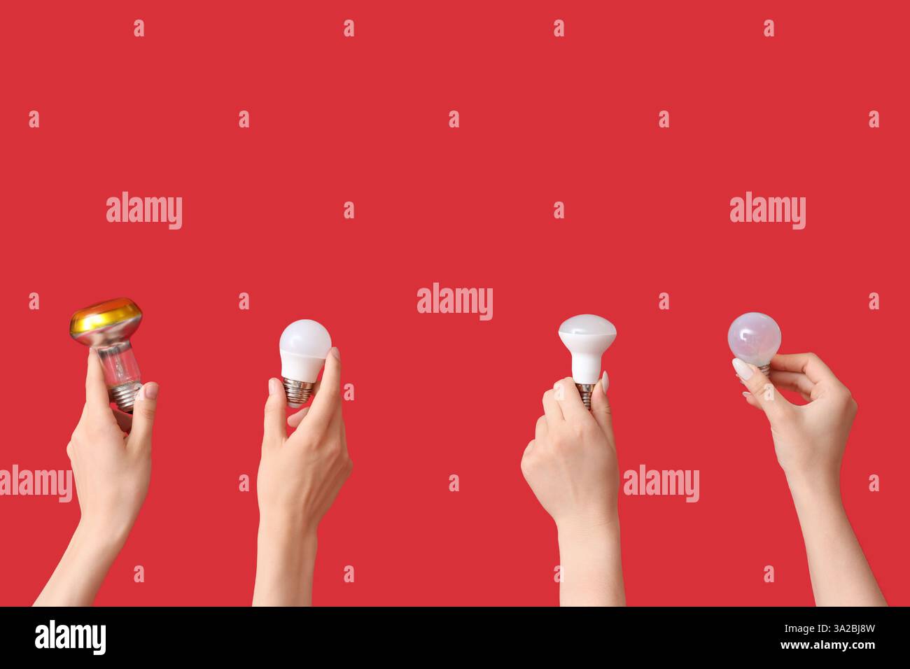 Electrician hands with different light bulbs on red background Stock Photo