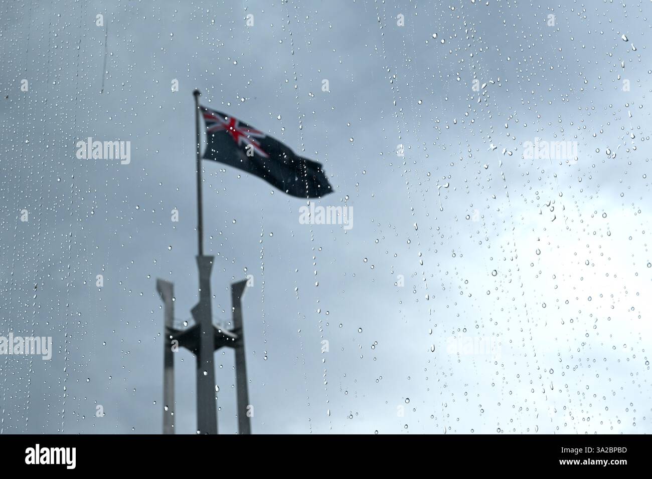 The flag pole of the Australian Parliament is seen through a rain ...