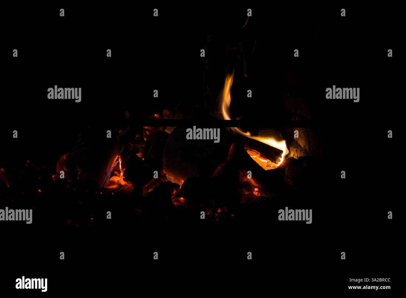 Charcoal and logs burning slowly in a campfire in the dark Stock Photo ...