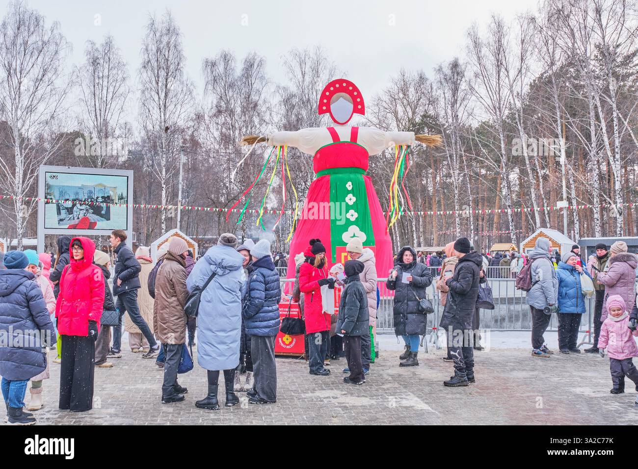 Yekaterinburg, Russia - February 26, 2025: People in warm clothing at traditional outdoor Slavic festival Farewell to winter. Large, colorful effigy s Stock Photo