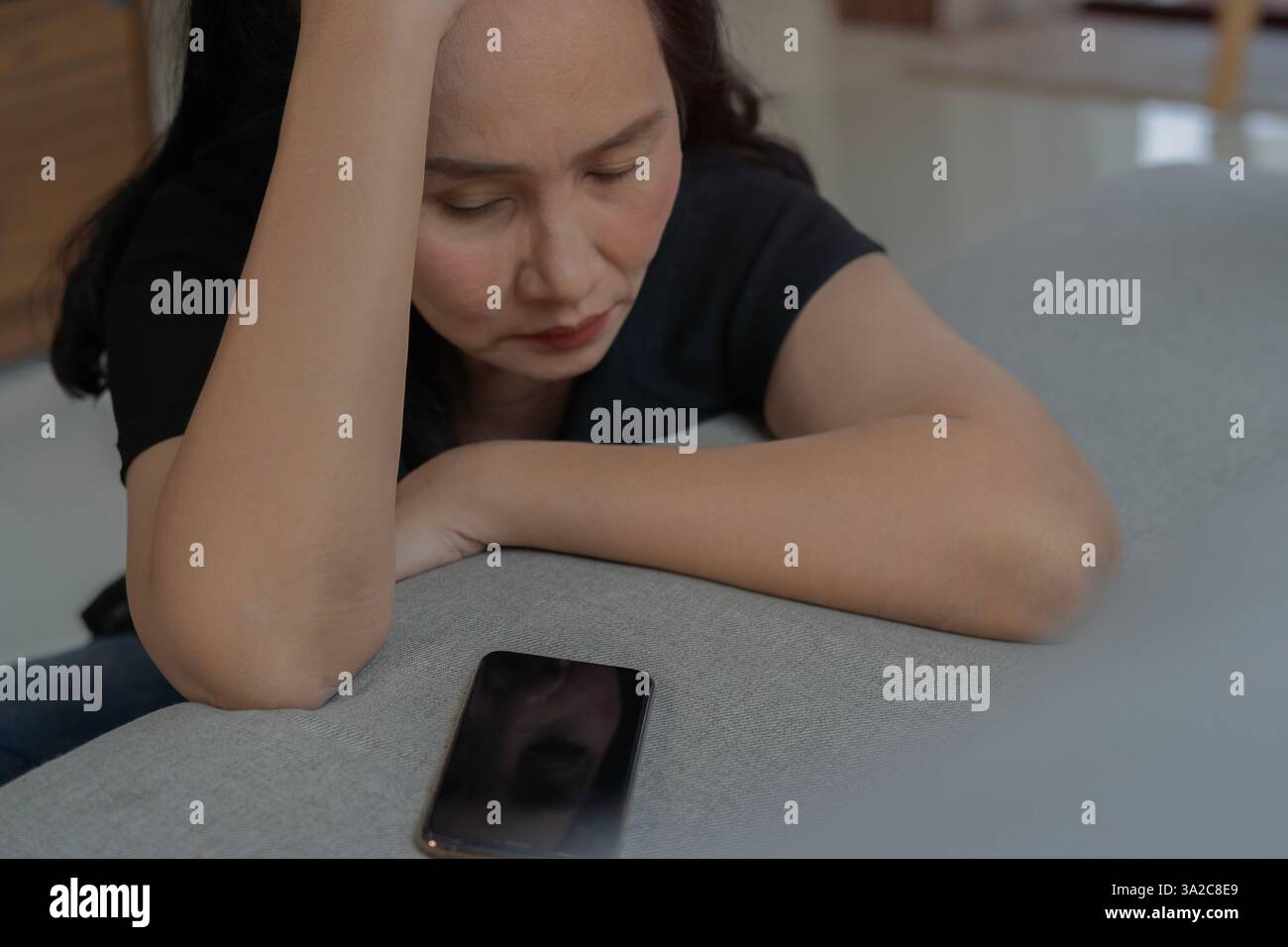 Cropped shot of dissatisfied mature Asian woman using smartphone indoors Bad News Concept. Selective focus. Stock Photo