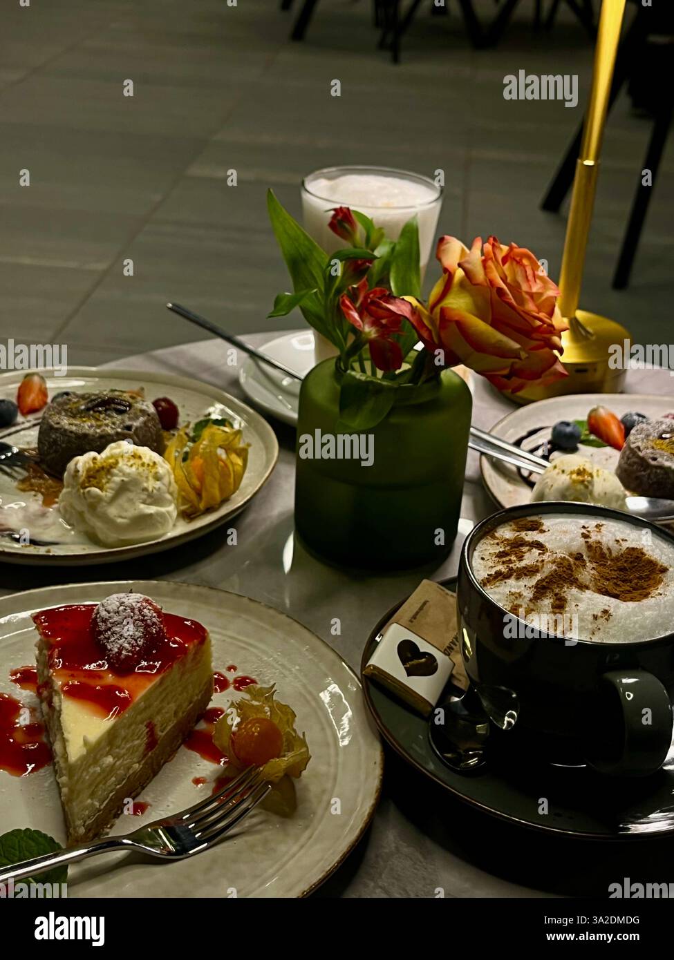 A cozy café table adorned with a variety of desserts and coffee cups, with a small flower in the center adding a touch of charm. - Smartphone Captured Stock Image