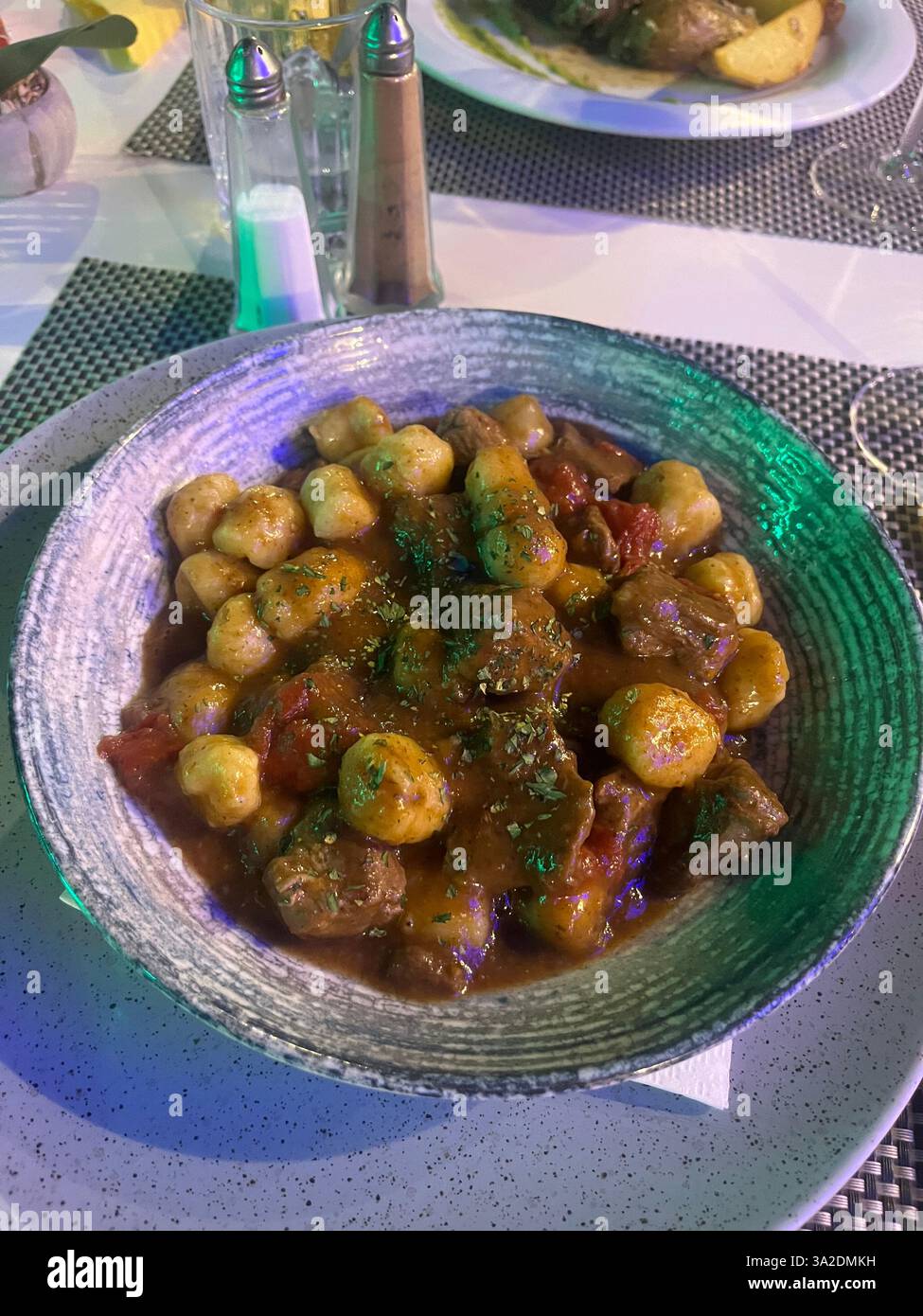 A comforting dish served in a cozy café, featuring tender meat accompanied by crispy potato balls, beautifully plated for a warm and inviting meal. - Smartphone Captured Stock Image