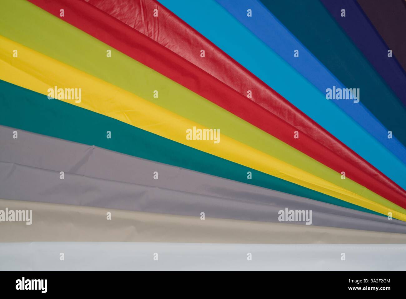 Vibrant fabric strips in a rainbow of colors and shades lie neatly ...