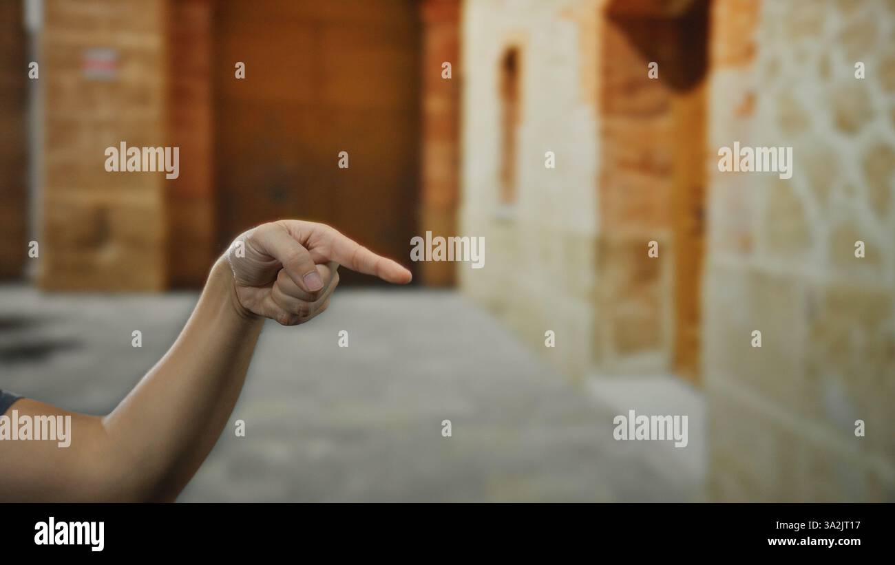 Man pointing hand outdoors on a city street set against a backdrop of aged stone buildings. Stock Photo