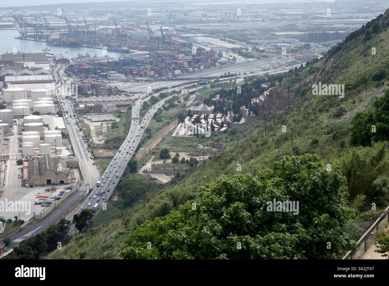 Logistics operations at a port with a highway and a natural hillside. Aerial perspective, traffic and vegetation Stock Photo