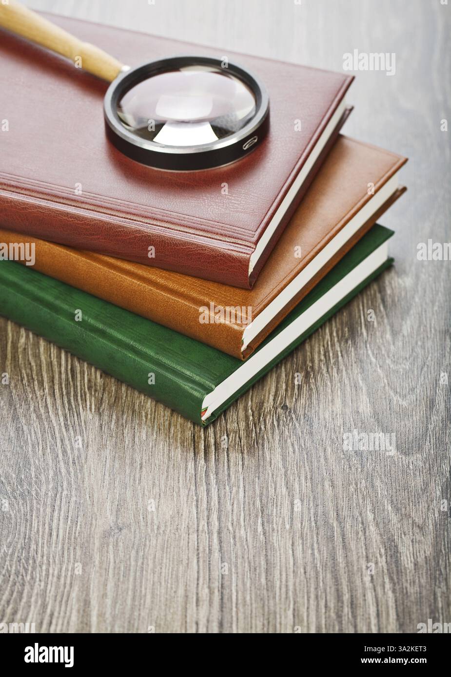 Three notebooks and magnifier Stock Photo