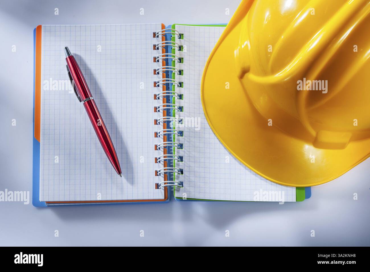 Safety hard hat checked notepad pen on white background Stock Photo