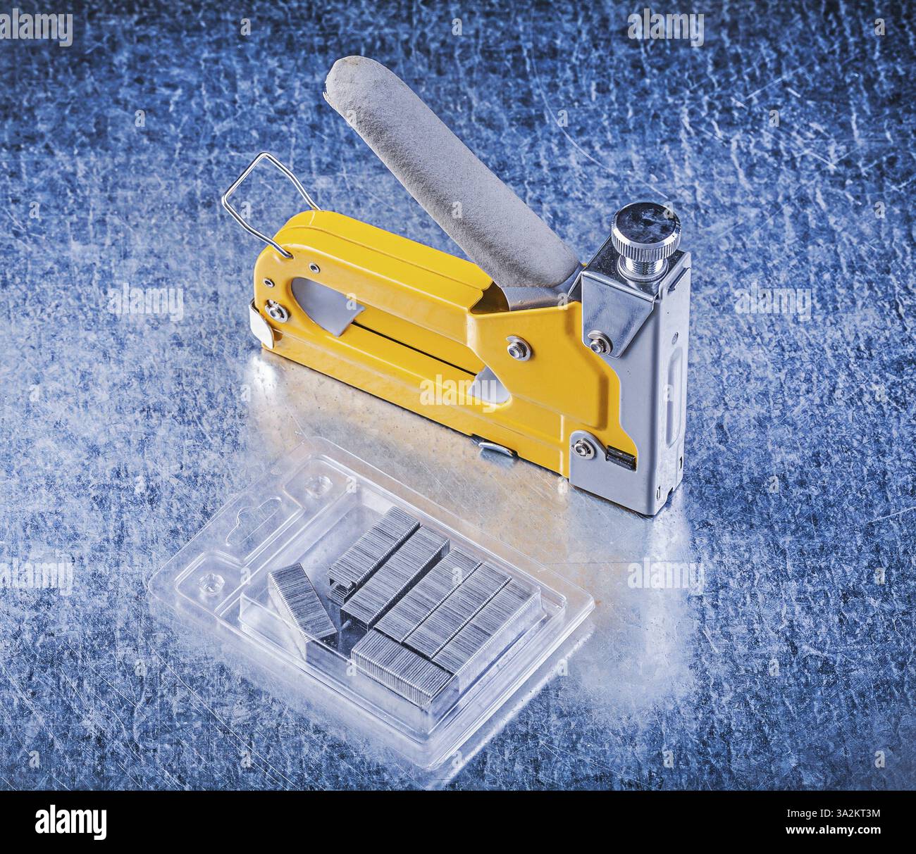 Stapler gun metal staples on metallic background Stock Photo