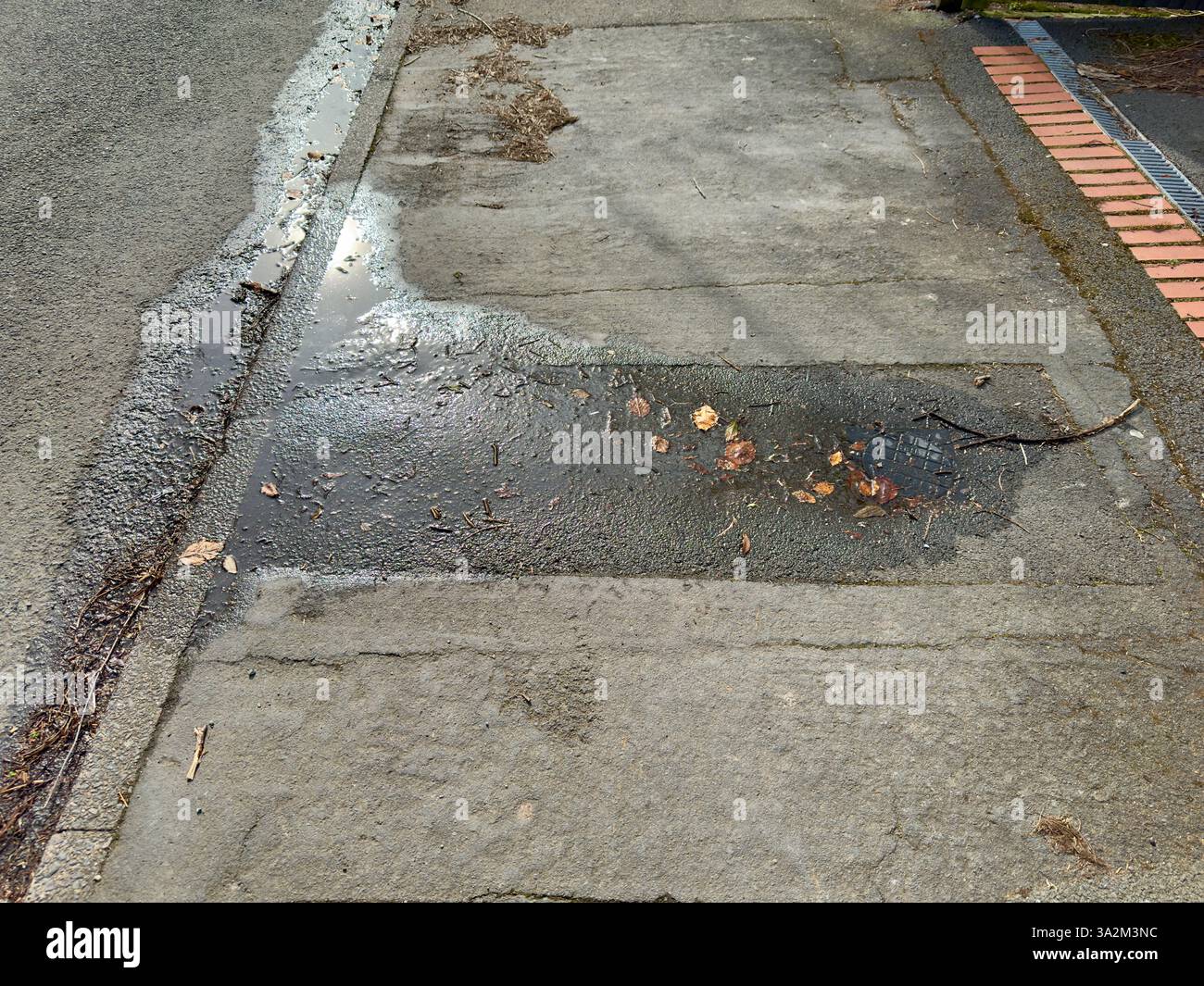 Water leaking out of a damaged pipe onto the footpath on an urban street. - Smartphone Captured Stock Image