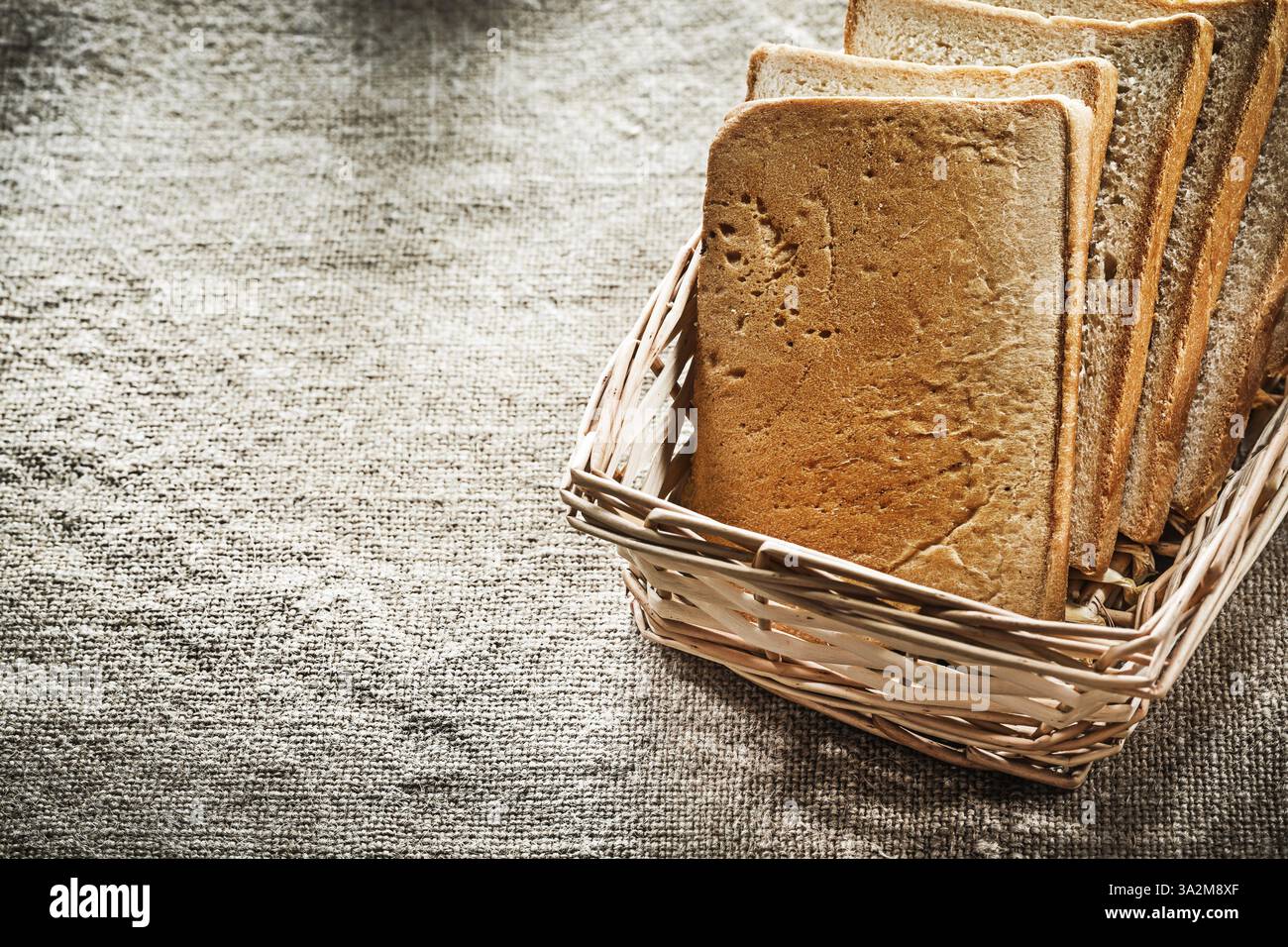 Wicker basket sliced bread on vintage sacking background Stock Photo