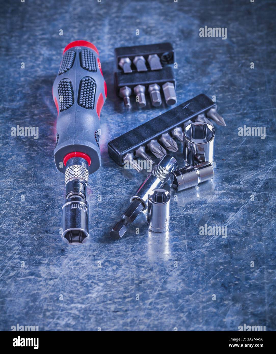 Screwdriver with rubber handle set of replaceable bits and heads on scratched metallic background construction concept Stock Photo