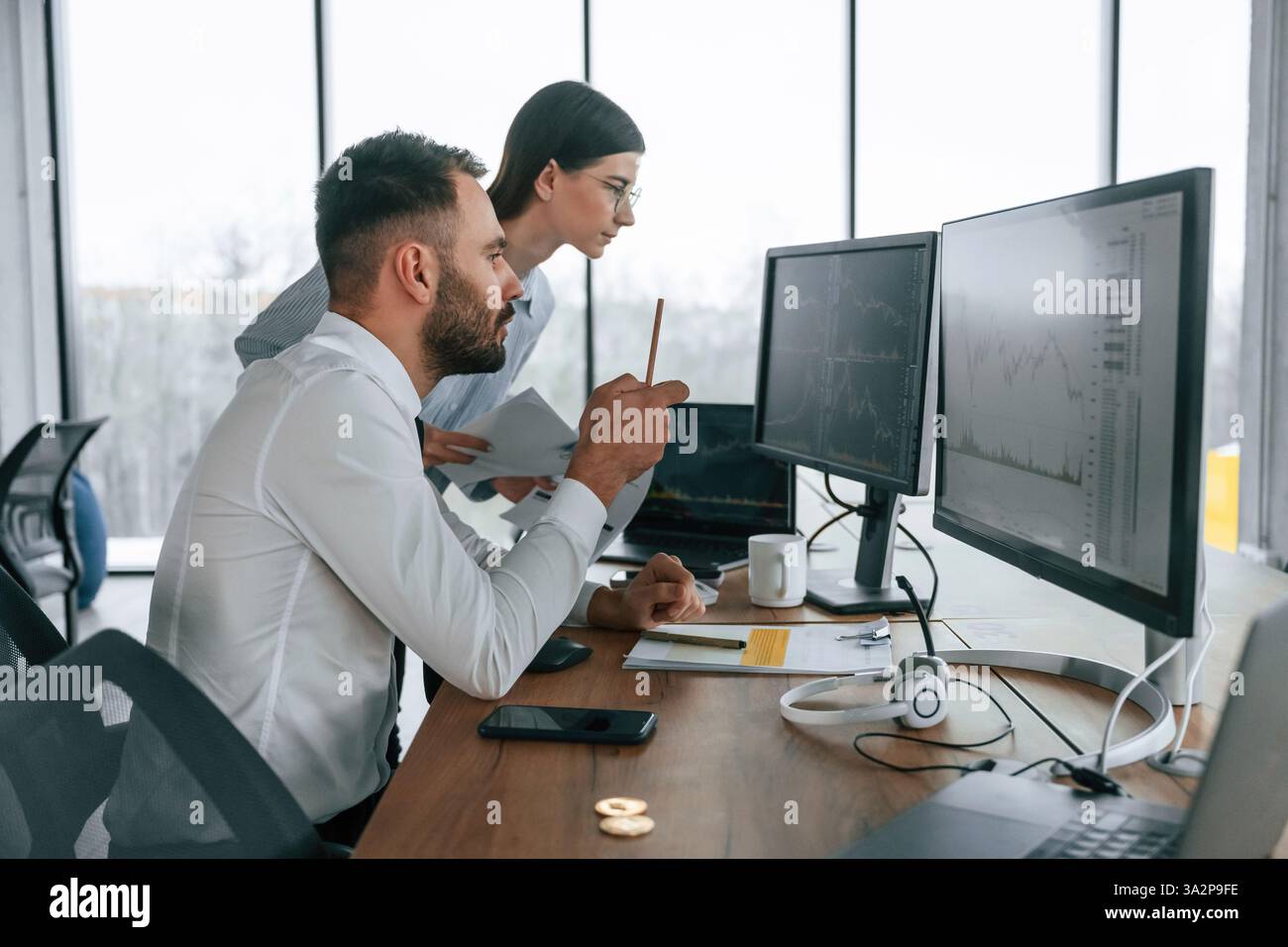 Working on a project together. Two employees are in the office. Stock Photo