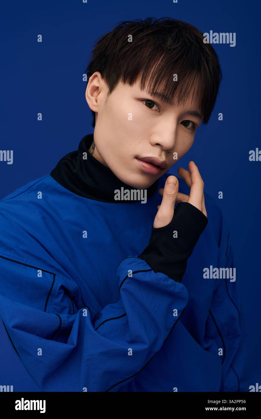 Handsome young Asian man elegantly poses in a vivid blue outfit ...