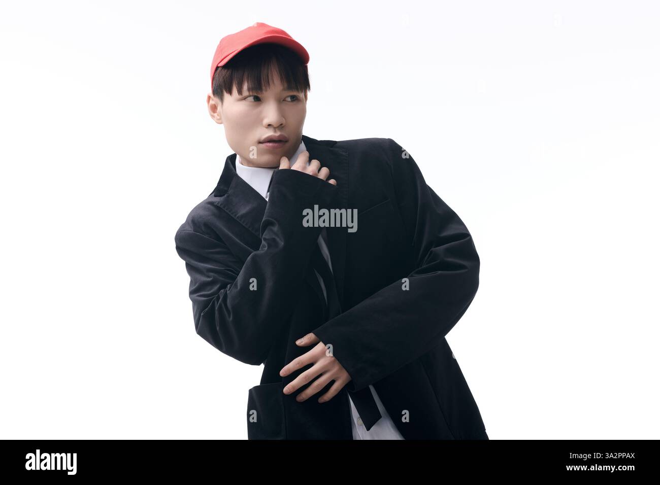 A young Asian man in a trendy outfit poses confidently with a playful ...