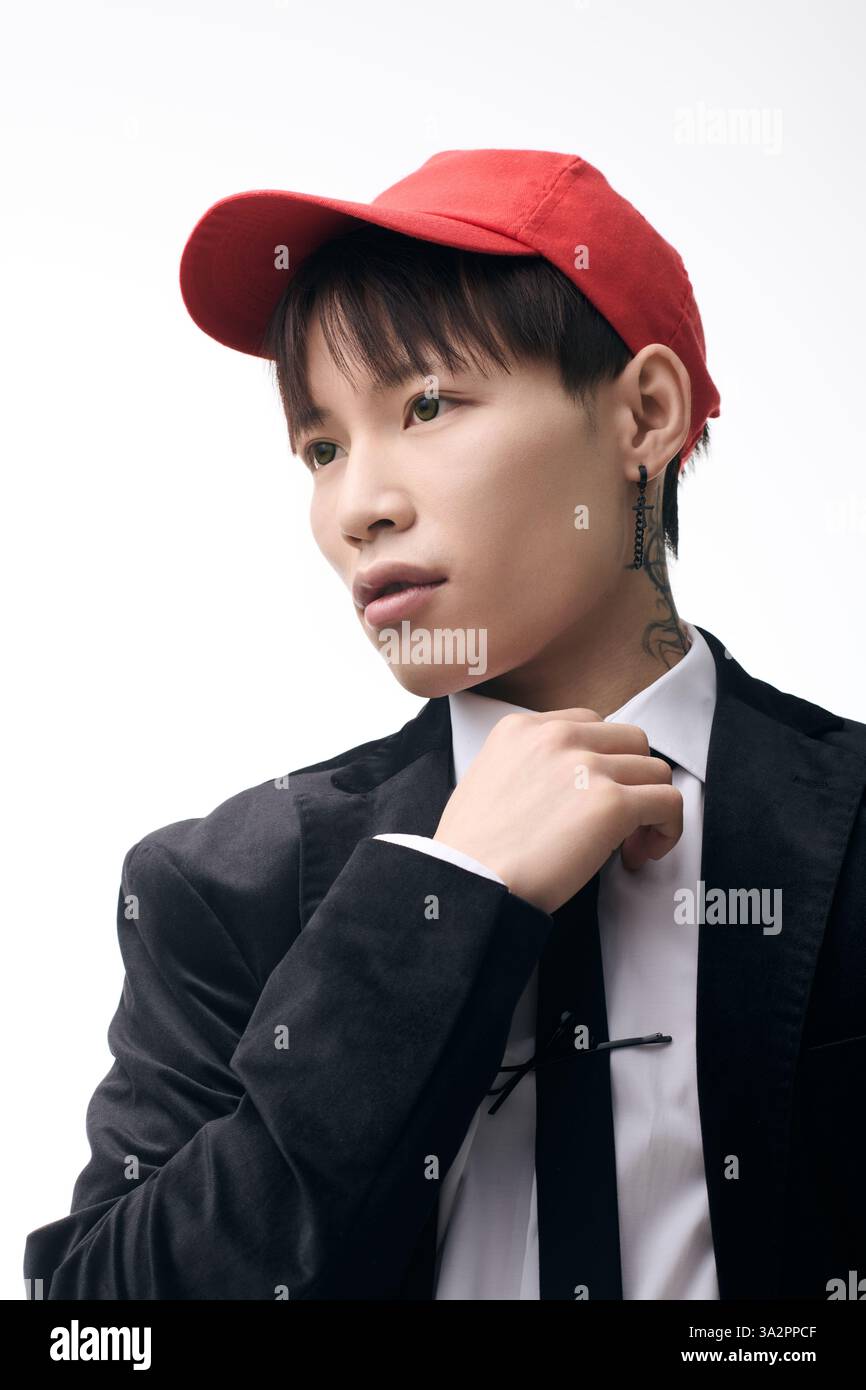 Sharp dressed young Asian man adjusts his tie with focus in a ...