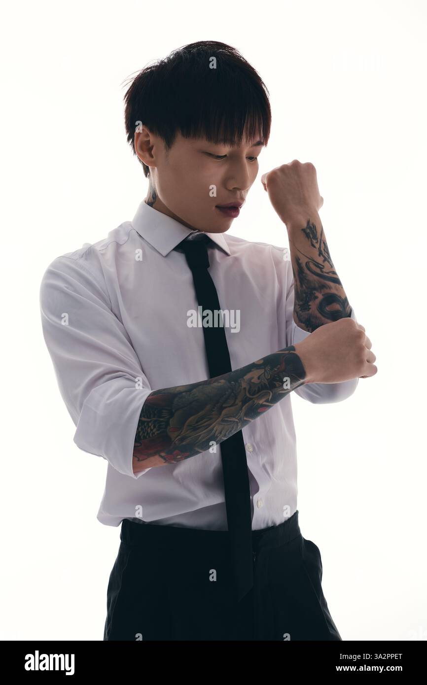 A stylish young Asian man adjusts his dress shirt, showing off ...