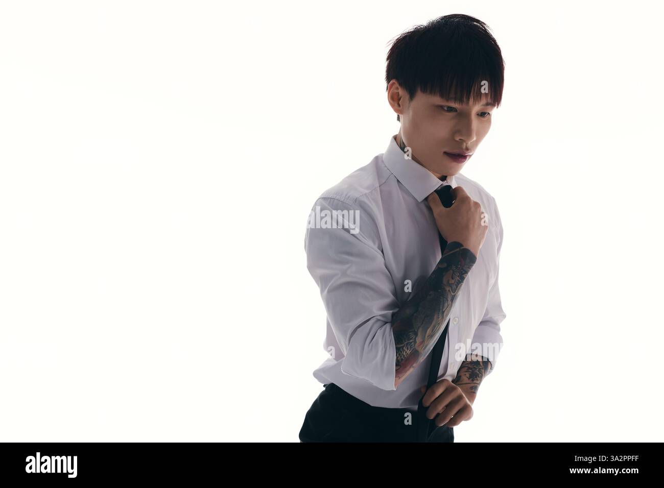 Confident young man in a white shirt and tie adjusts his attire while ...