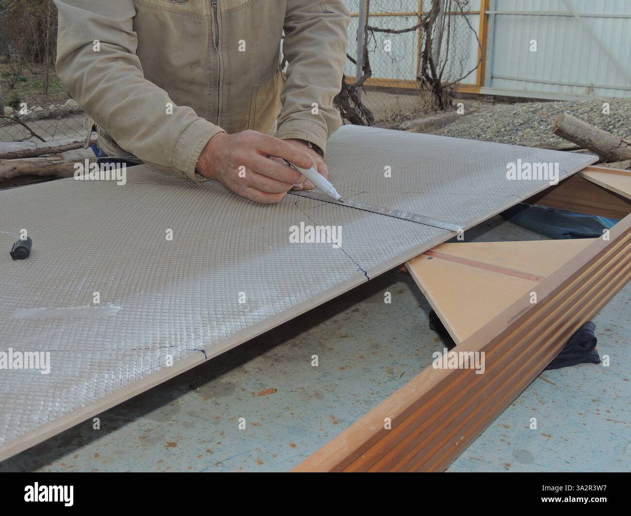 tiler draws a line with a marker on a large finishing tile using a ...