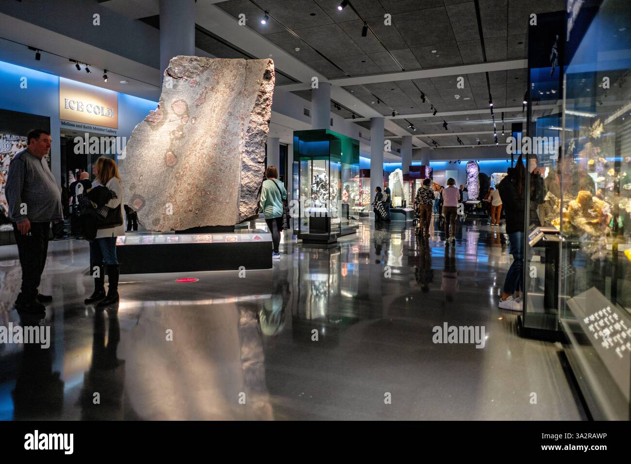 American Museum Of Natural History Gems And Minerals Hall New York City // NEW YORK CITY, United States — The interior of the Allison and Roberto Mignone Halls of Gems and Minerals at the American Museum of Natural History shows the exhibition space with the massive amethyst geode from Uruguay visible in the background. Reopened in June 2021 after a complete redesign, the 11,000-square-foot exhibition space features more than 5,000 specimens from 98 countries. The renovated halls employ specialized lighting techniques and modern display methods to showcase the institution's world-renowned mine Stock Photo
