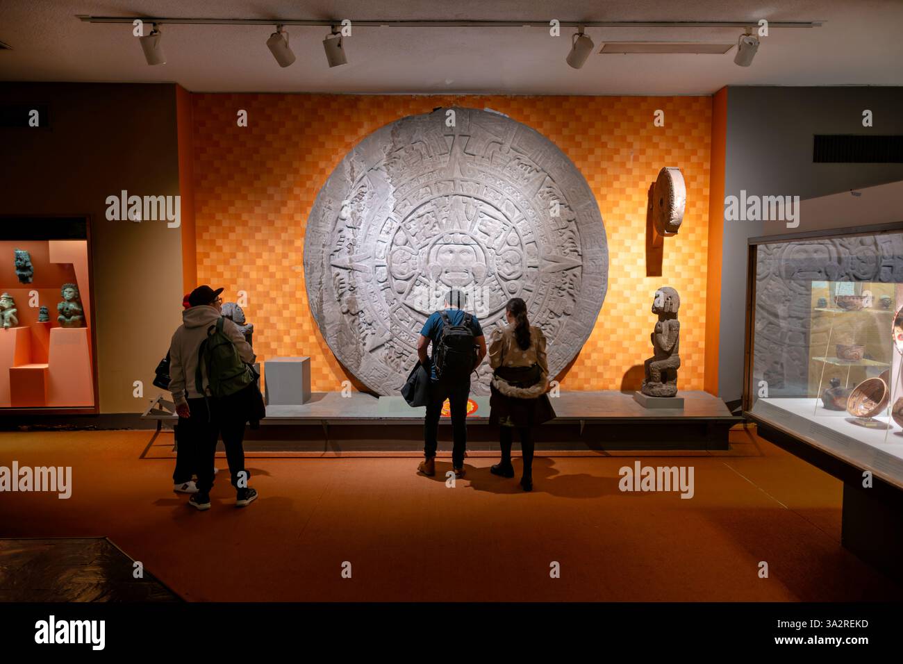 Aztec Stone Of The Sun Replica American Museum New York City // NEW YORK, United States — A full-size reproduction of the Aztec Stone of the Sun is displayed at the American Museum of Natural History. The replica faithfully represents the original 20-ton porphyry monolith discovered in 1790, which measures approximately 12 feet in diameter and features complex solar symbolism central to Aztec religious beliefs. Originally installed in the ceremonial center of Tenochtitlan, the actual Stone of the Sun now resides in Mexico City's National Museum of Anthropology, while this detailed reproduction Stock Photo