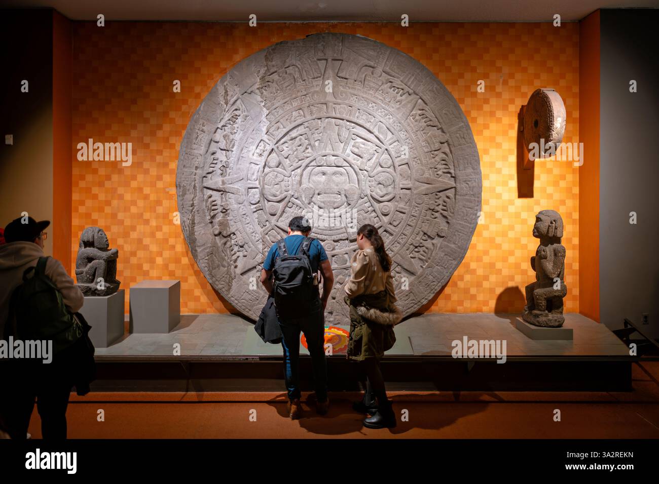 Aztec Stone Of The Sun American Museum Of Natural History New York City // NEW YORK, United States — A full-size reproduction of the Aztec Stone of the Sun is displayed at the American Museum of Natural History. The replica faithfully represents the original 20-ton porphyry monolith discovered in 1790, which measures approximately 12 feet in diameter and features complex solar symbolism central to Aztec religious beliefs. Originally installed in the ceremonial center of Tenochtitlan, the actual Stone of the Sun now resides in Mexico City's National Museum of Anthropology, while this detailed r Stock Photo