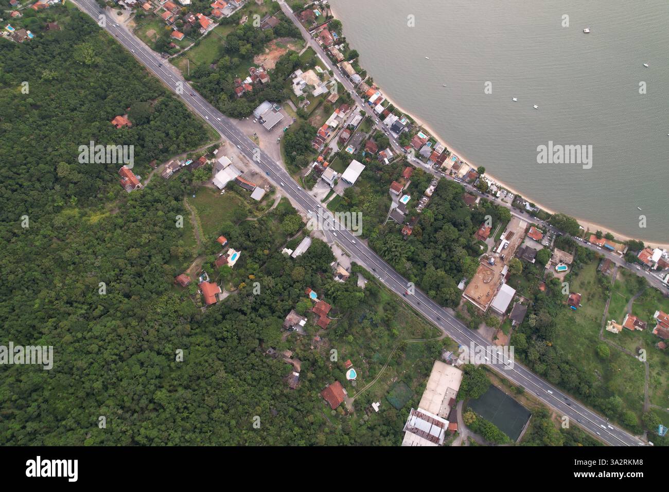 Aerial view of coastal road and residential area near a water body ...