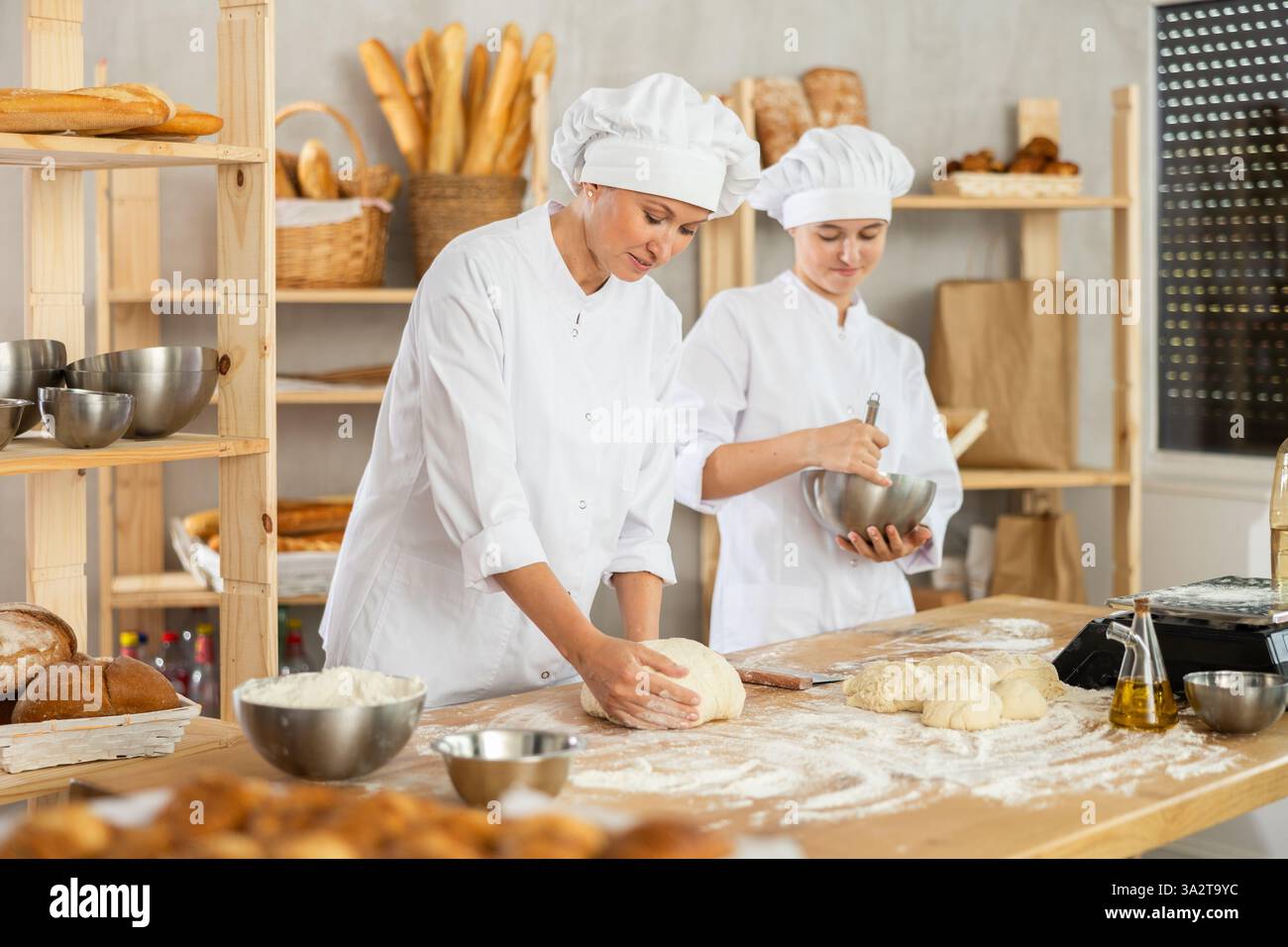 Female bakers in uniform preparing gray dough Stock Photo