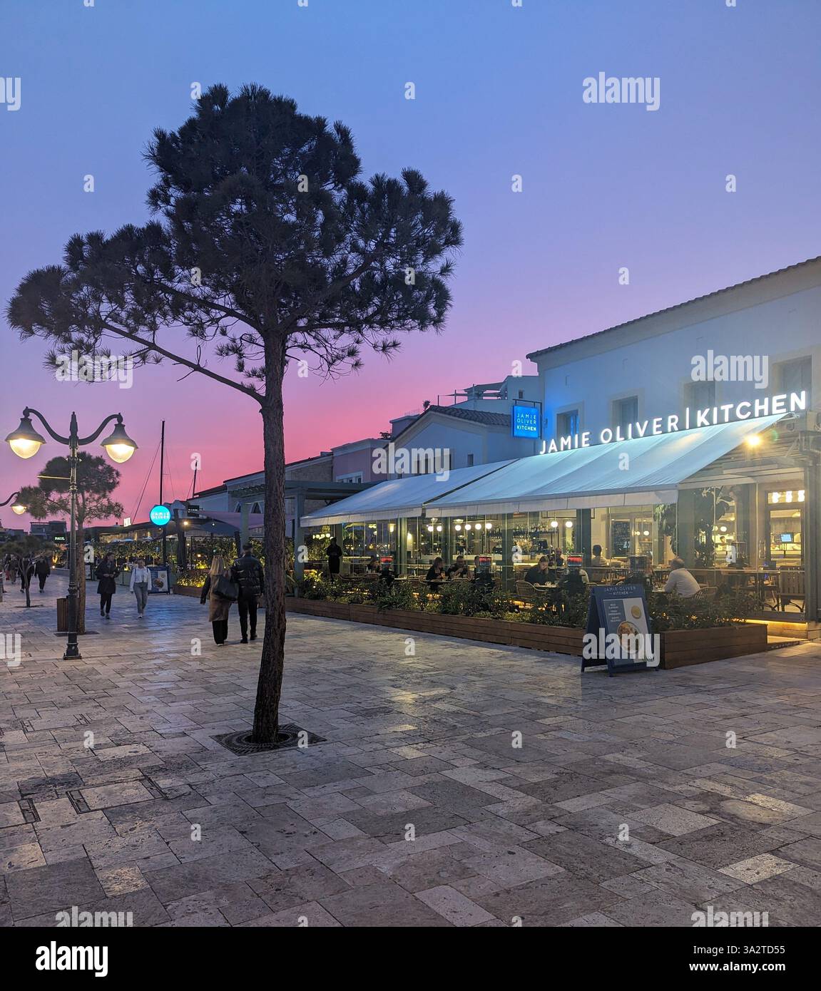 Jamie Oliver Kitchen restaurant at sunset in Larnaca, Cyprus, with a glowing sky and relaxed evening vibe along the promenade. - Smartphone Captured Stock Image