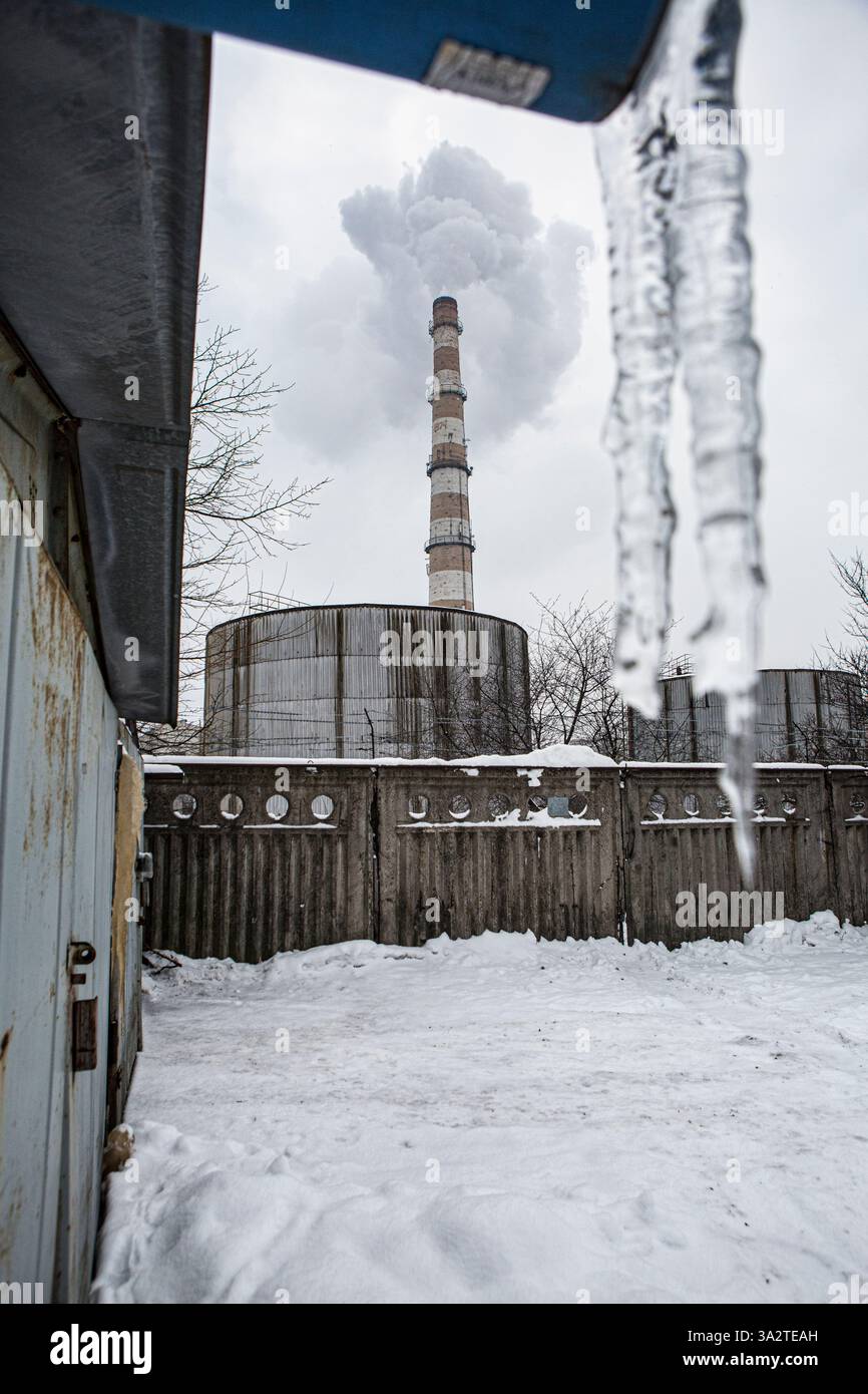 Global warming and my garage. As local utility station pipe is puffing CO2 in the sky,2lovely icicles hung from the roof that warm albeit snowy winter Stock Photo