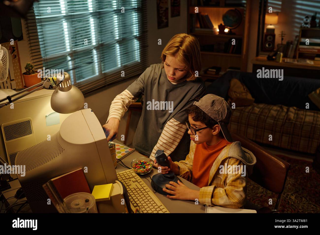 Two children engaging with vintage computer while sitting at desk in ...