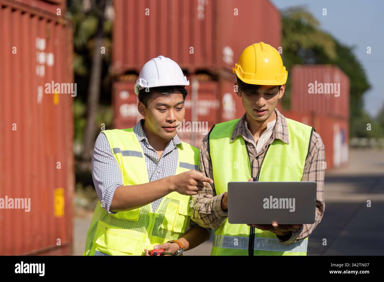 Digital Collaboration. Engineers using technology for logistics planning outdoors. Stock Photo