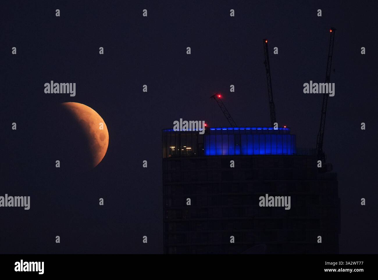 A lunar eclipse is visible above Canary Wharf in London as the full ...