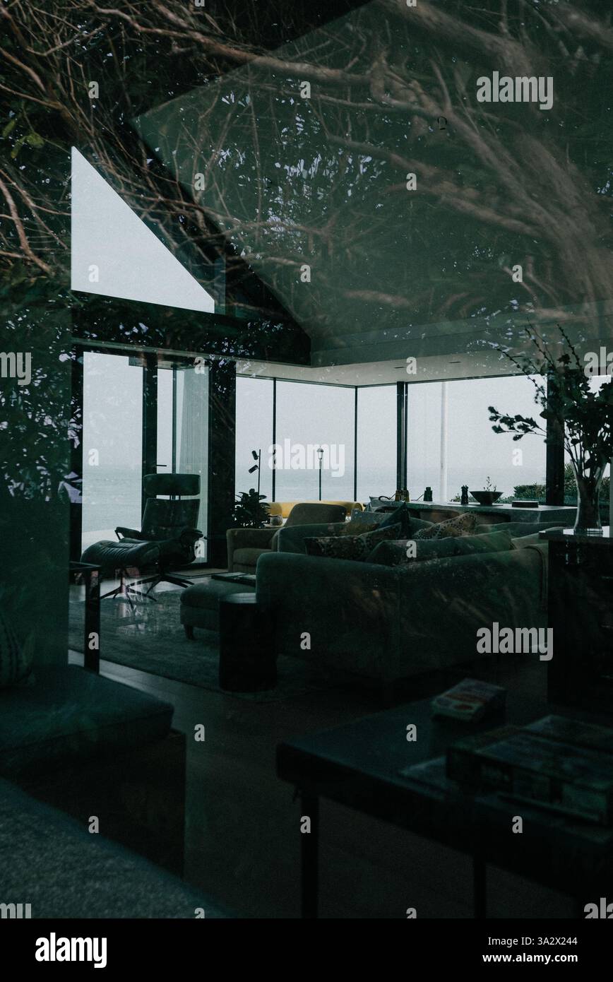 A living room with a large window overlooking the ocean. The room is ...